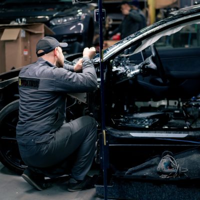 a mechanic at a service station repairs a part in a car that is completely disassembled into parts