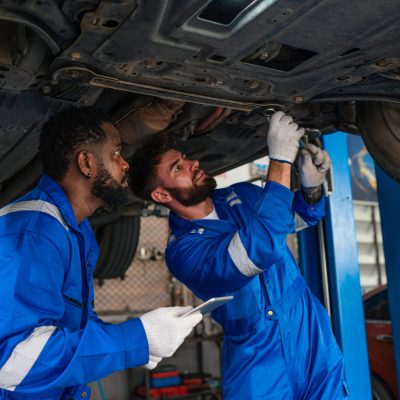Team Auto mechanic in blue uniform are repair and maintenance auto engine is problems at car repair shop.